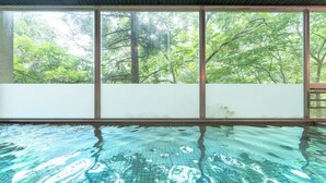 Piscina con vistas a árboles a través de amplias ventanas.