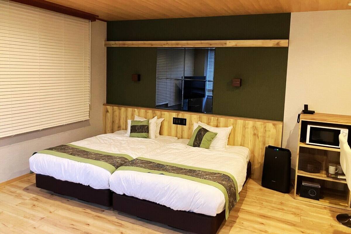 A double bed with a wooden headboard, a bedside table, and a built-in TV shelf.