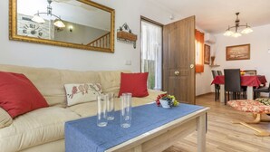 Ein Wohnzimmer mit Sofa, Couchtisch mit Gläsern, Spiegel und Essbereich mit Stühlen und Tisch.