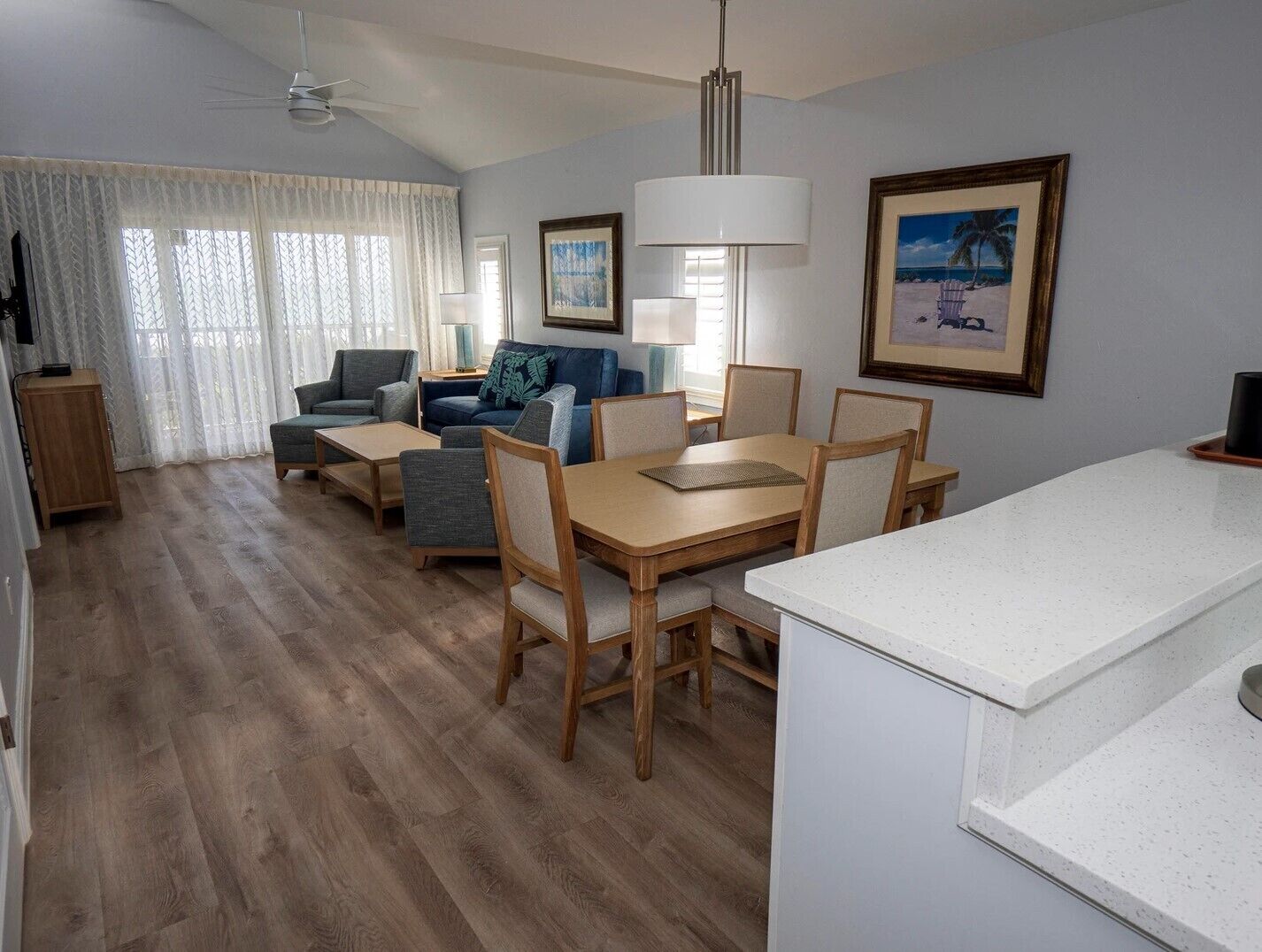 A modern living room with a dining area, wooden flooring, and a kitchen counter.