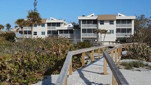 Une propriété située en bord de mer, avec une promenade en bois menant à un bâtiment doté de plusieurs balcons.