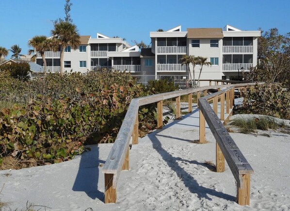 A beachfront property with a wooden boardwalk leading to a building with multiple balconies. - Sanibel, Shell Island Beach Club, Oceanfront
Near Lighthouse (Sanibel)