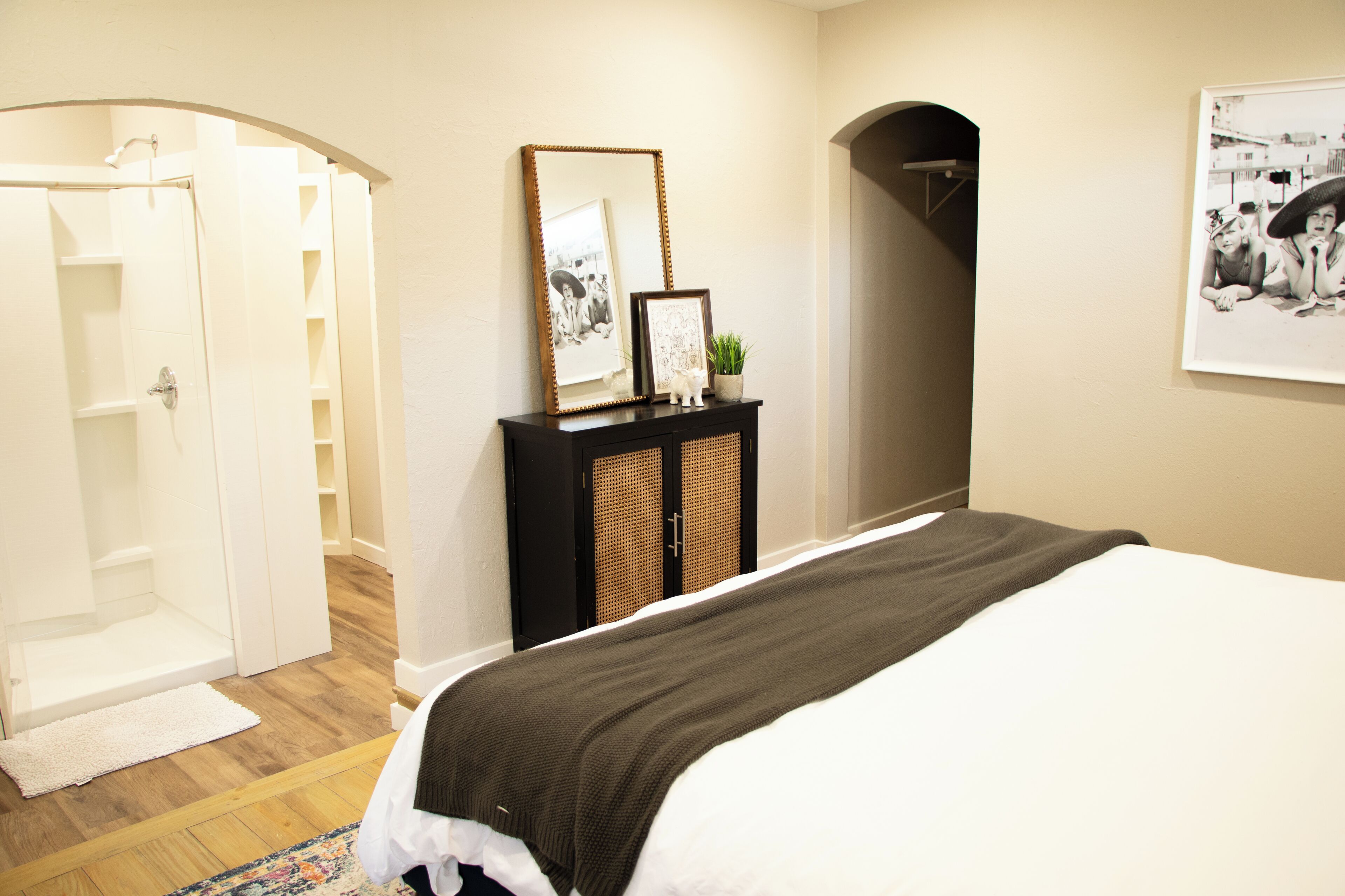 Une chambre à coucher comprenant un lit, une commode, un miroir et une porte donnant sur une salle de bain.