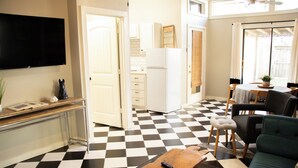 A modern kitchen with a checkered floor, a dining area with a table and chairs, and a living room with a sofa and a coffee table.