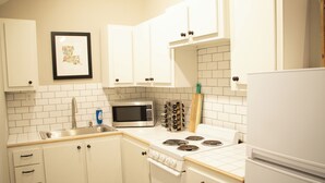 A kitchen with white cabinets, a microwave, a stove, and a refrigerator.