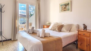 Une chambre d’hôtel avec un lit, une table de chevet, une armoire en bois, un tableau au mur et une vue sur l’extérieur par la fenêtre.