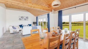 A spacious room with a wooden dining table, chairs, and a large window offering a view of the outdoors.
