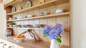 A wooden shelf with various ceramic dishes and a vase with flowers.
