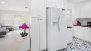 Una cocina moderna con armarios blancos, un refrigerador y una cafetera.