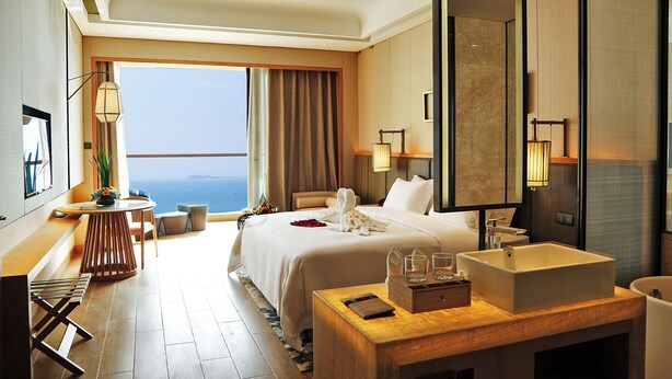 Ein Hotelzimmer mit Bett, Schreibtisch mit Stuhl, Bad und Meerblick.