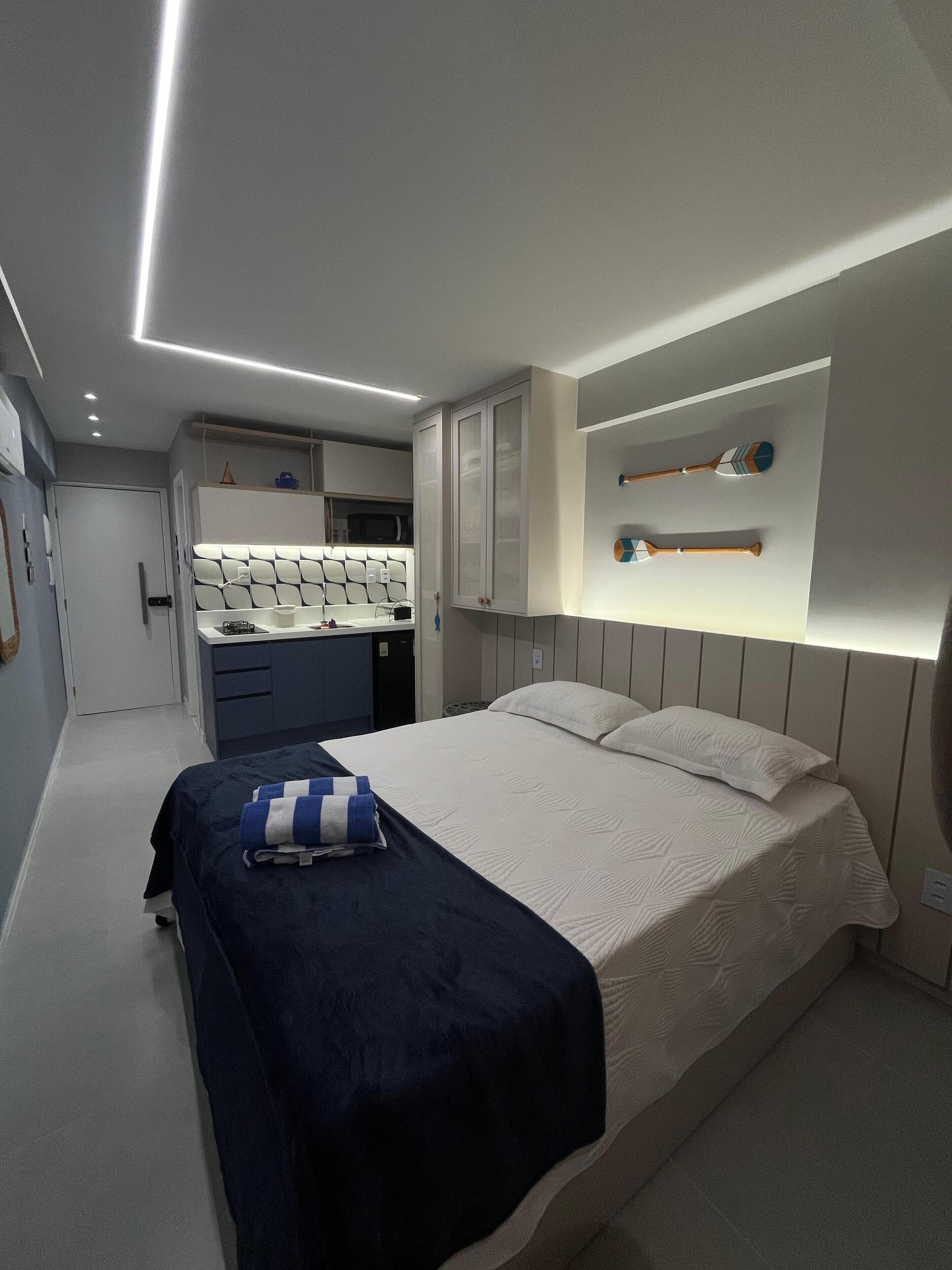 A modern bedroom with a neatly made bed, a bedside table, and a built-in wardrobe.