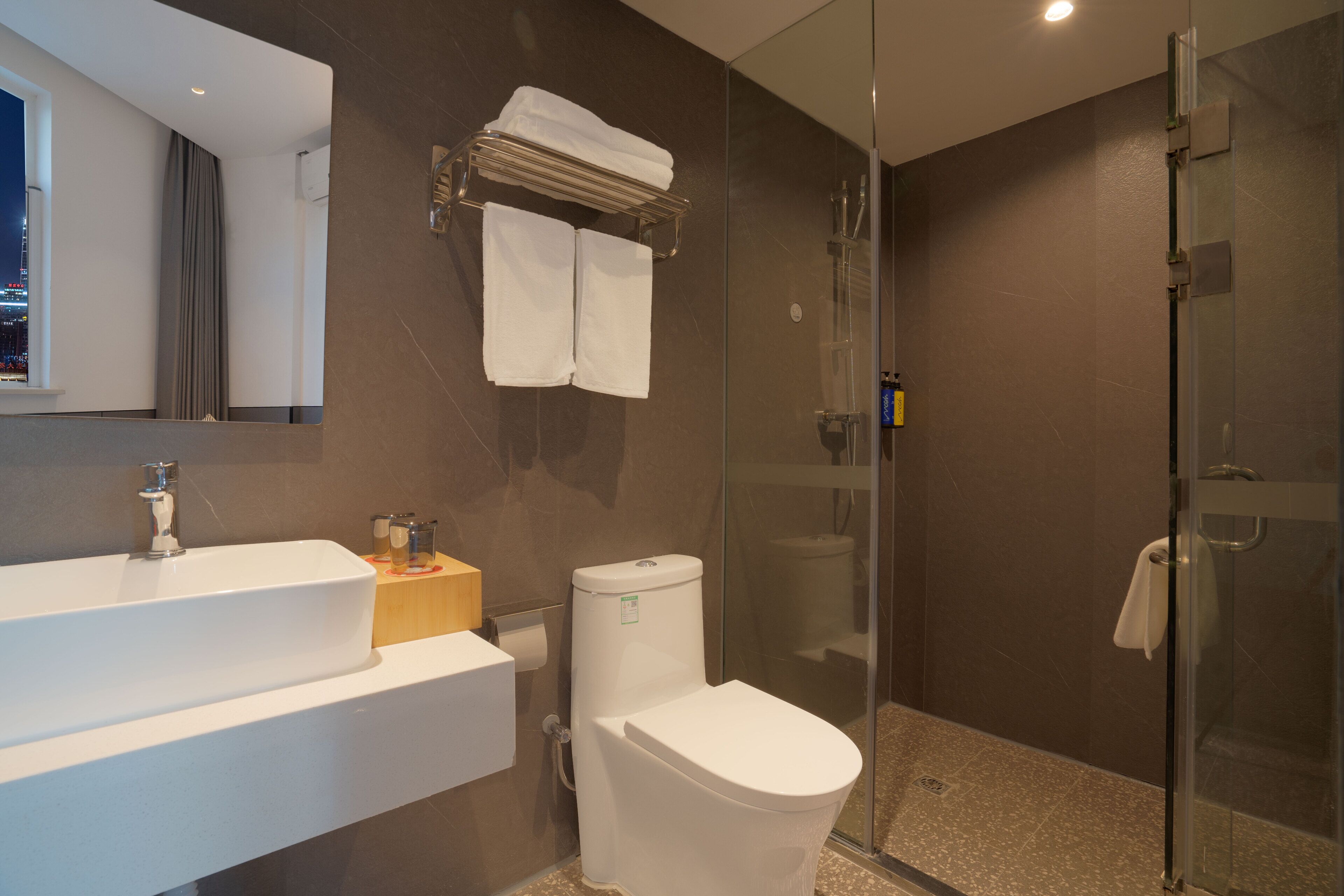 Un bagno moderno con cabina doccia in vetro, lavandino bianco e water.