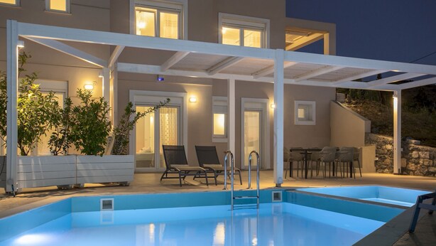 Ein Pool mit weißem Pergola, Sitzgelegenheiten im Freien und einer Steinmauer.
