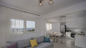 Ein modernes Wohnzimmer mit grauem Sofa, einem Holztisch und Blick auf die Küche und den Essbereich.