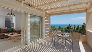 A balcony with a view of the sea, a glass door leading to a living area, and a table with chairs. - Blue Hills Villas by Estia Orange 1 (Malevizi)