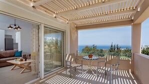 A balcony with a view of the sea, a table with chairs, and a sofa with a coffee table. - Blue Hills Villas by Estia Yellow 2 (Malevizi)