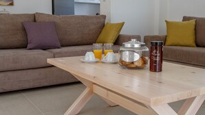 A modern living room with a wooden coffee table, two sofas, and a kitchen in the background. - Blue Hills Villas by Estia Yellow 2 (Malevizi)