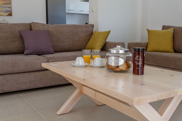 A modern living room with a wooden coffee table, two sofas, and a kitchen in the background.