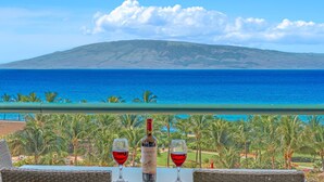 Ein Balkon mit Blick auf das Meer und ein Berg, zwei Gläser Rotwein und eine Flasche Alamos Wein.