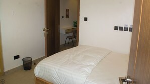 A bedroom with a bed, a desk, and a chair. - 1BD Serenity Dubai Suites (Abuja)