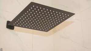 A black, perforated metal shower tray mounted on a white marble wall. - 1BD Serenity Dubai Suites (Abuja)