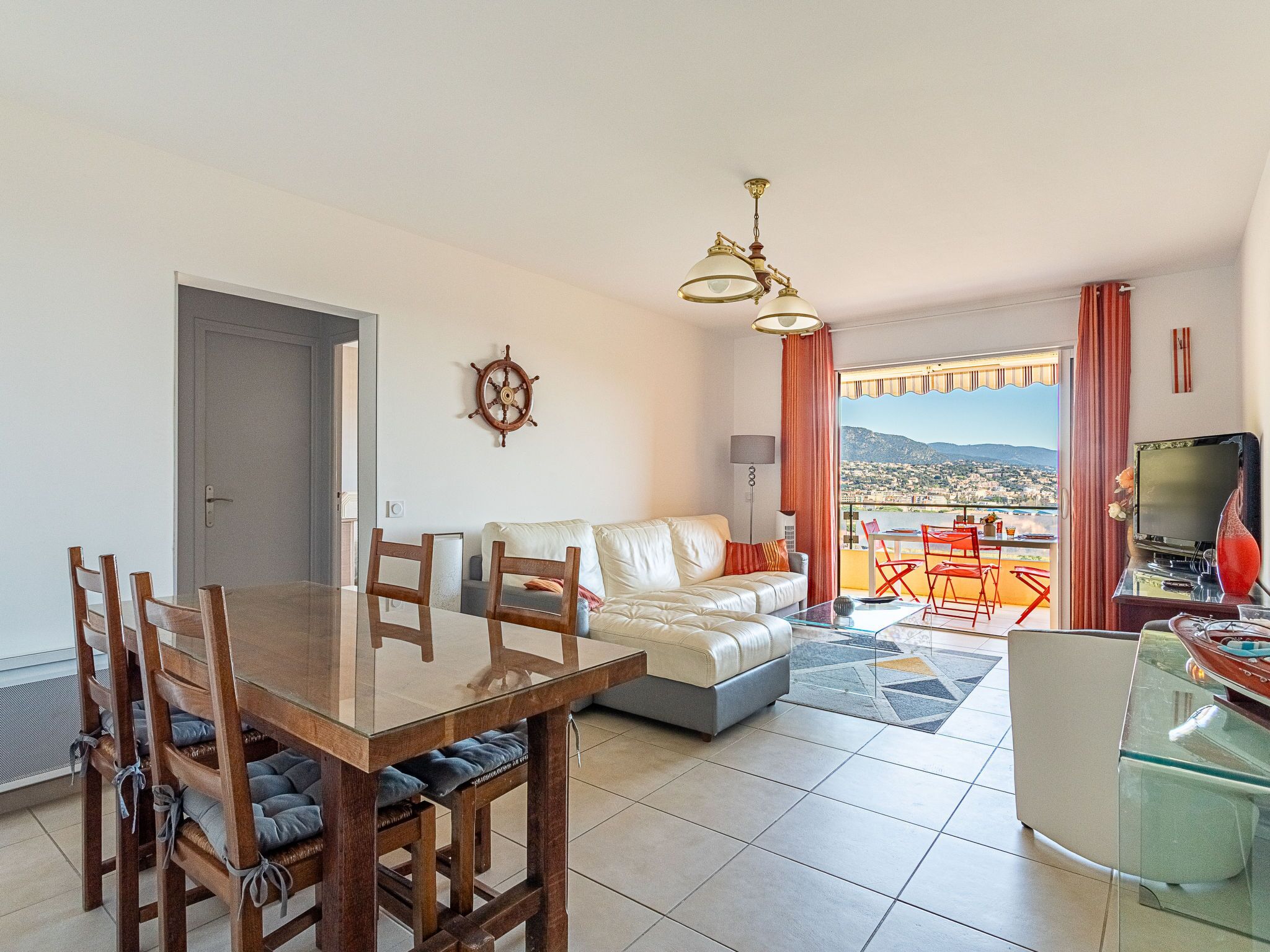 Ein modernes Wohnzimmer mit Essbereich, einer Couch, einem Fernseher und Blick auf die Stadt.
