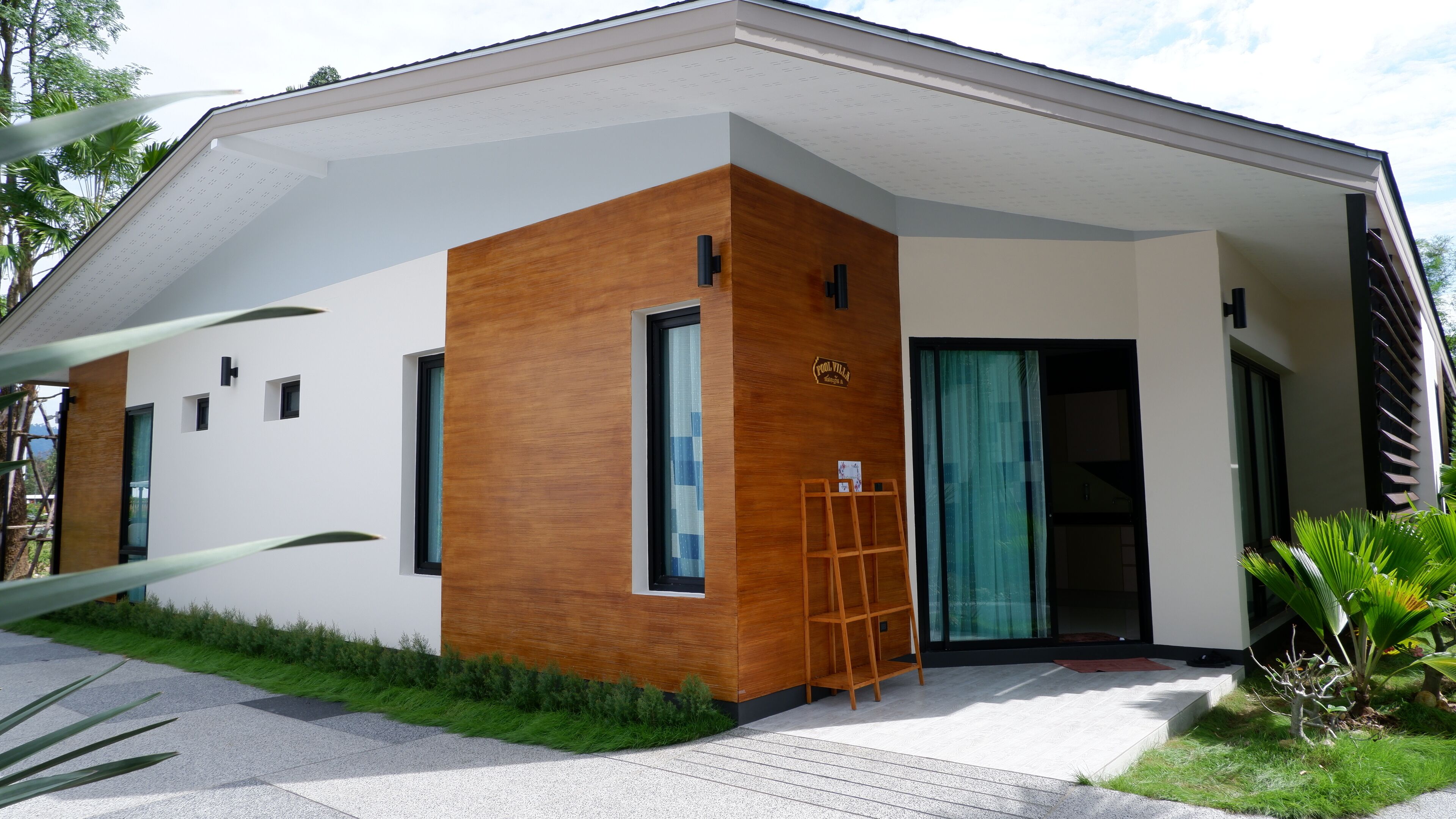 Una casa moderna con fachada blanca, un revestimiento de madera y un amplio ventanal.