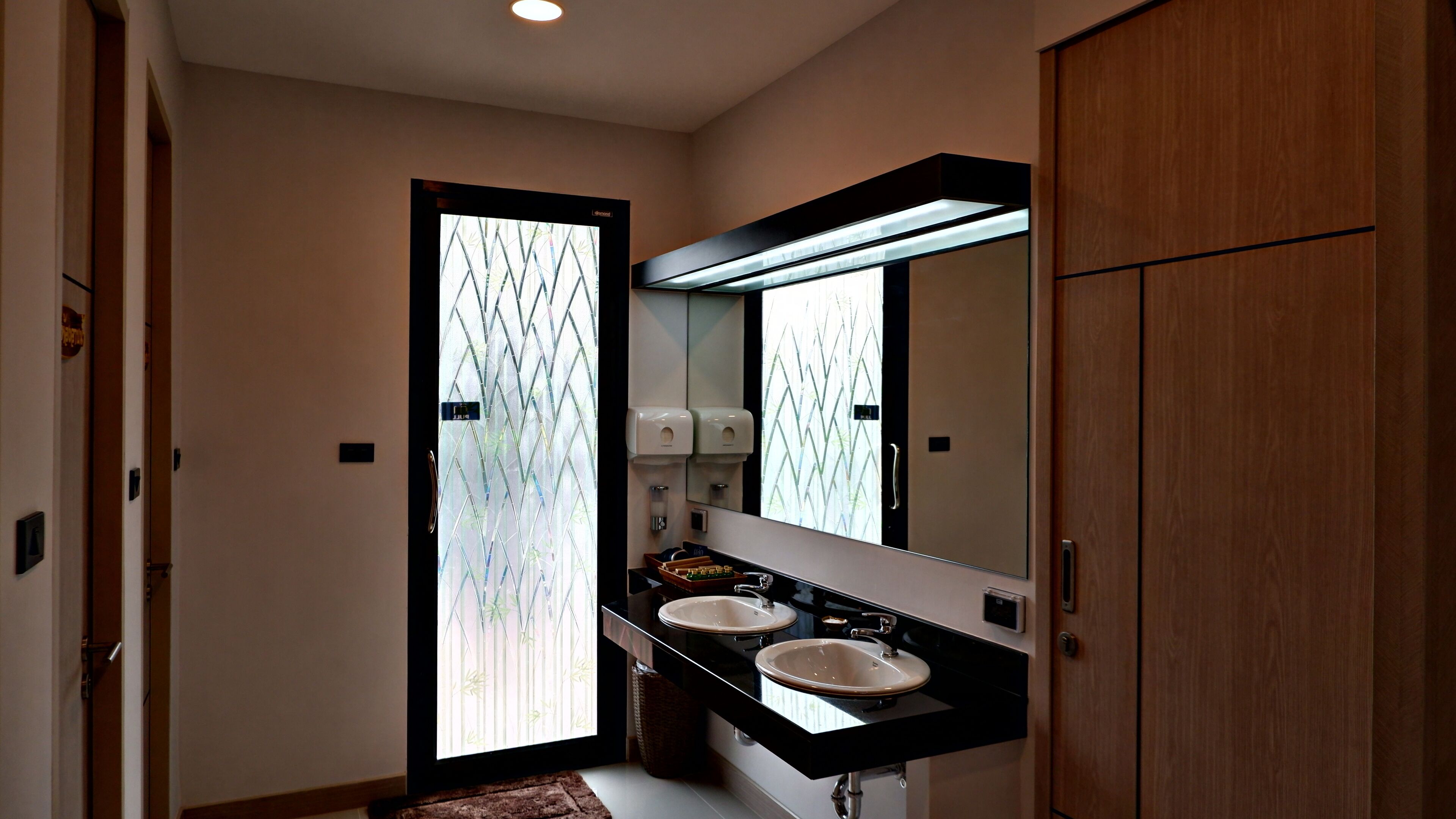 Un baño moderno con dos lavamanos, un espejo grande y un mueble de madera.