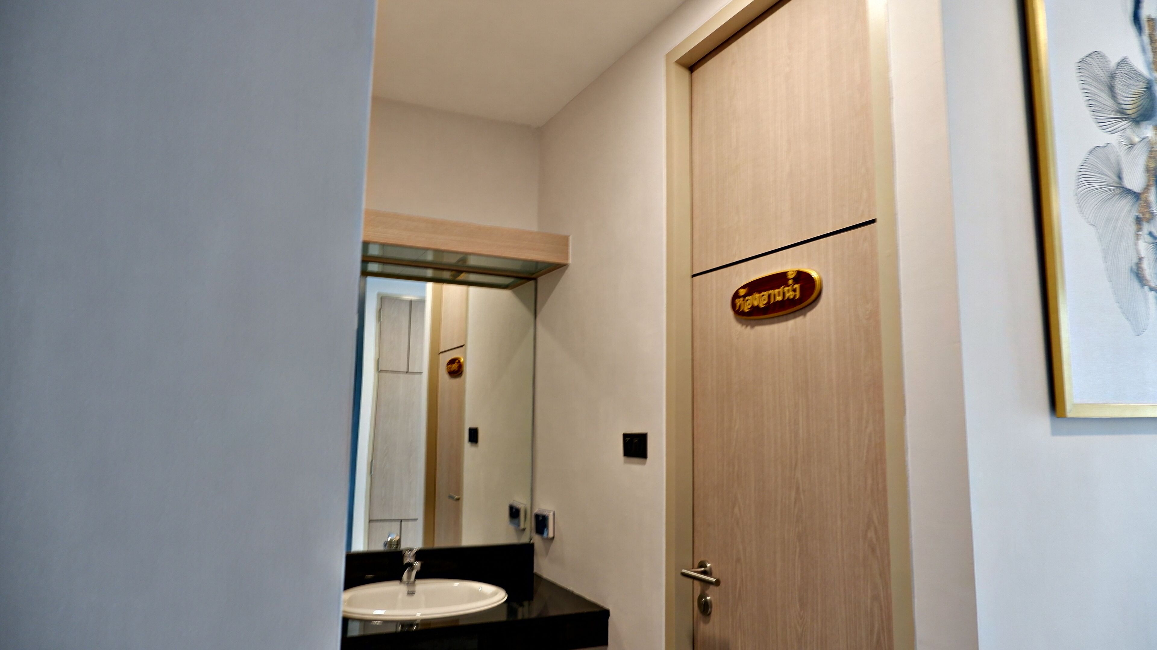 A bathroom with a sink, mirror, and a door with a sign.