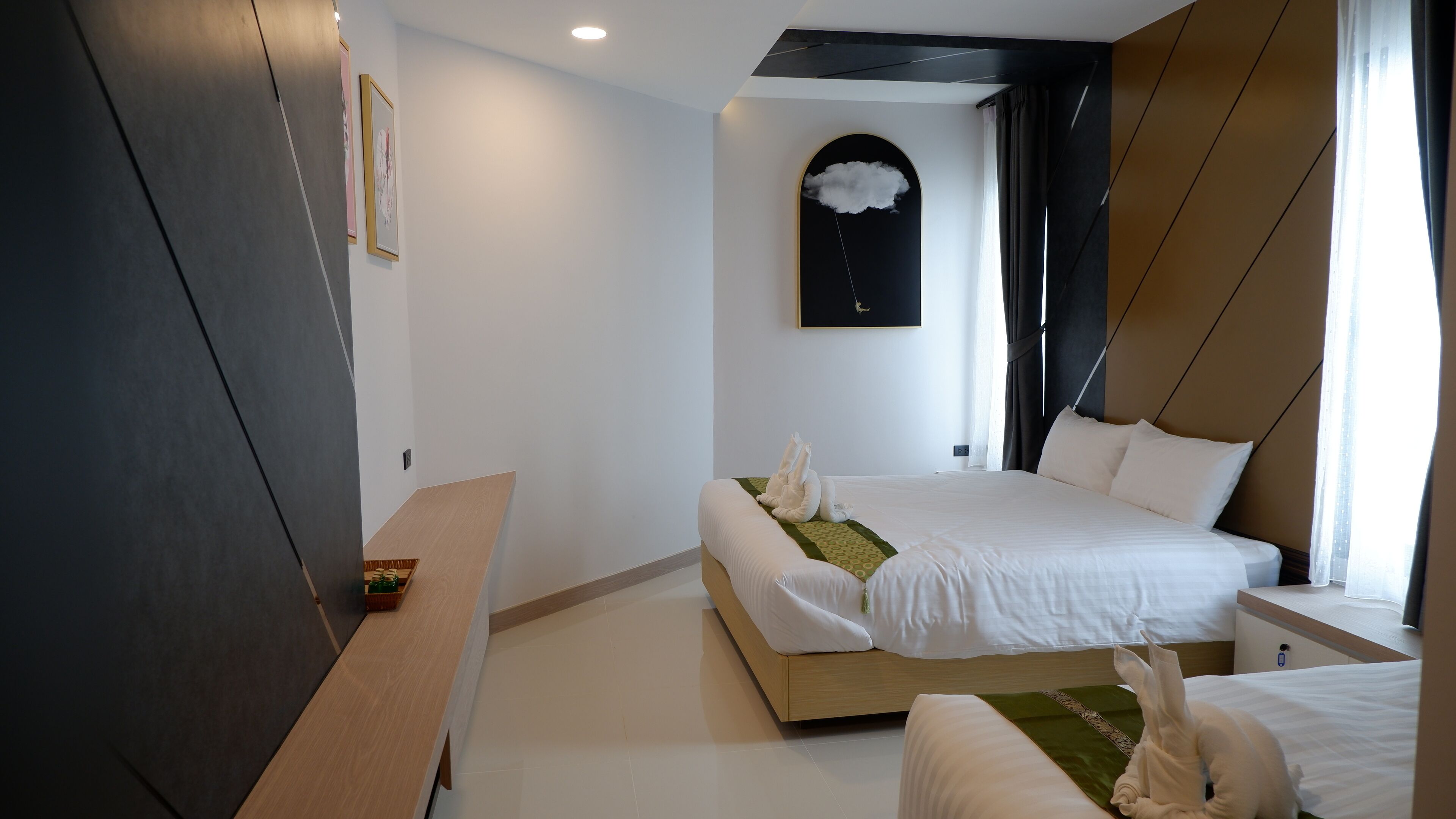 A modern hotel room with a bed, bedside table, and a small seating area.