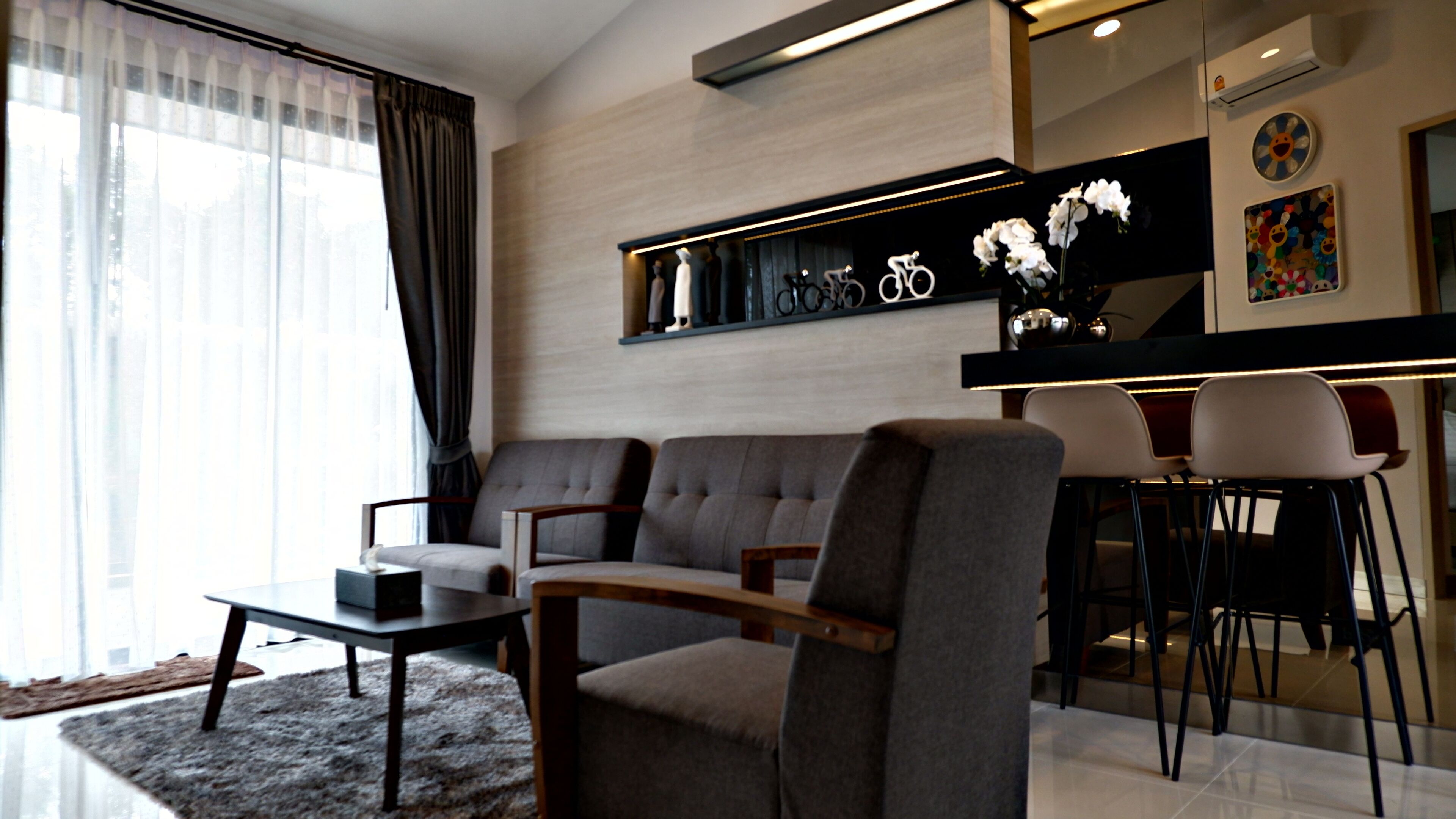 Un salon moderne comprenant un canapé, des fauteuils, une table basse et un coin repas avec des chaises et un bar.