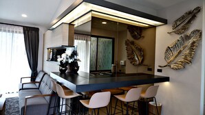 A modern kitchen with a bar area, a dining set, and decorative leaf wall art. - TheRabbithome (Nakhon Nayok)