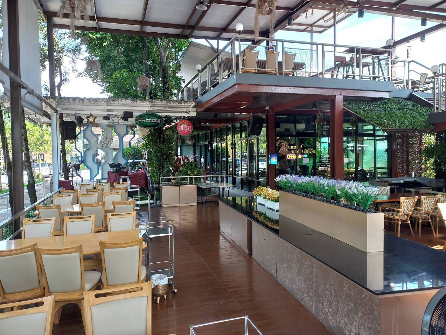 Ein Restaurant mit überdachter Außenbestuhlung, einer Bar und Blick auf die Straße.