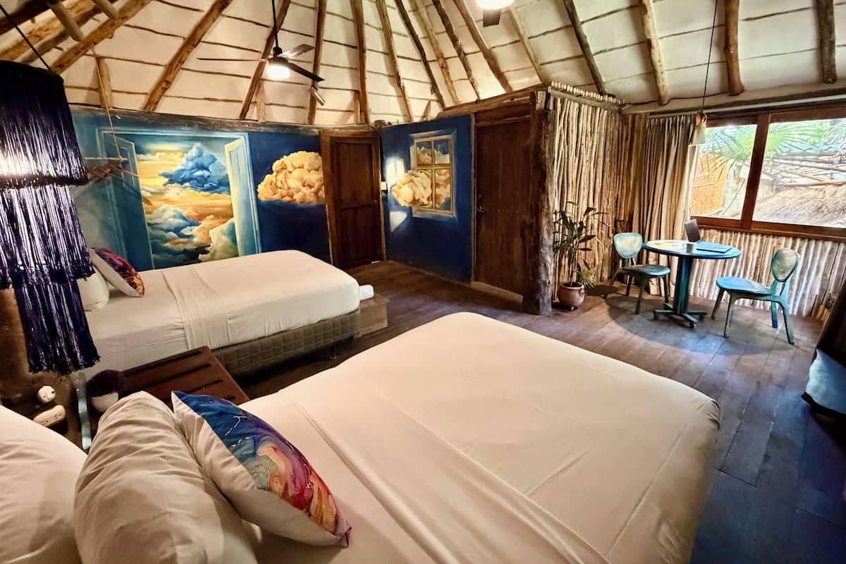 A tent-style accommodation with two beds, a dining area, and a view of the outdoors.