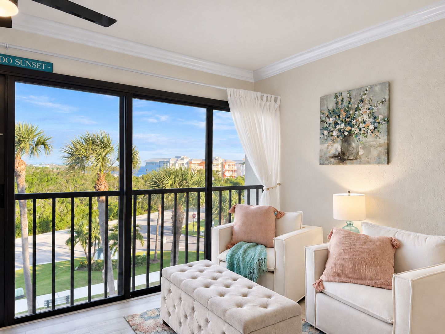 A living room with a large window, a sofa, a loveseat, and a decorative painting.