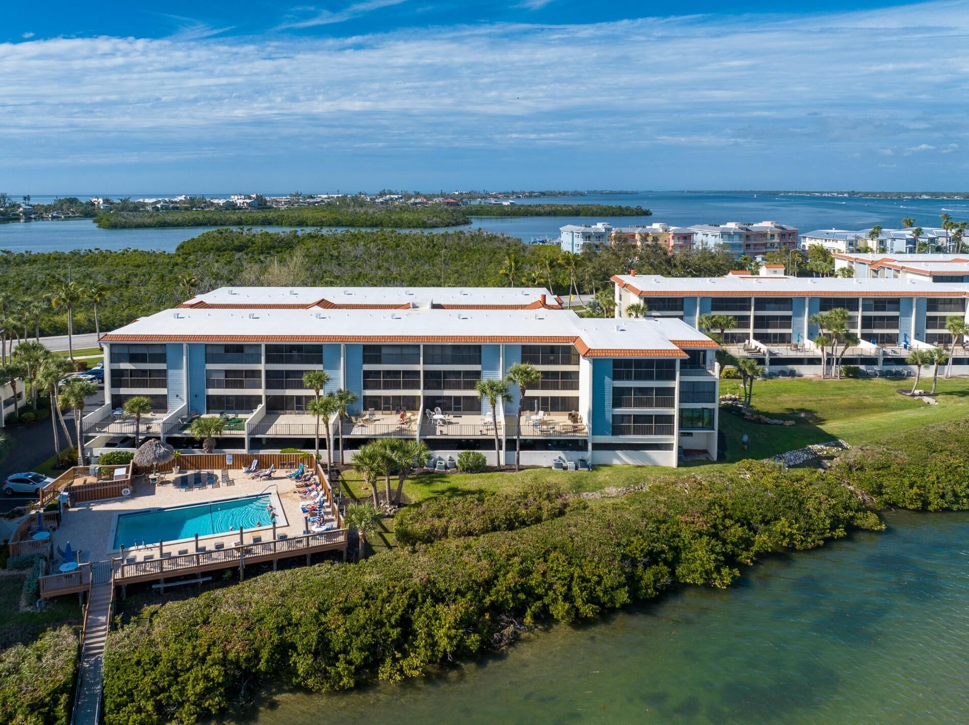 A resort with a pool, multiple buildings, and a view of the ocean.