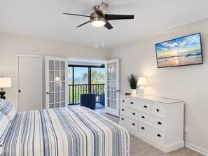 Une chambre à coucher avec un lit, un ventilateur de plafond, une commode, un téléviseur et un balcon avec vue.