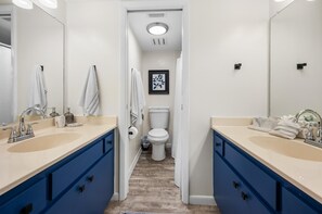 Un baño moderno con dos lavamanos, armarios azules y un inodoro.