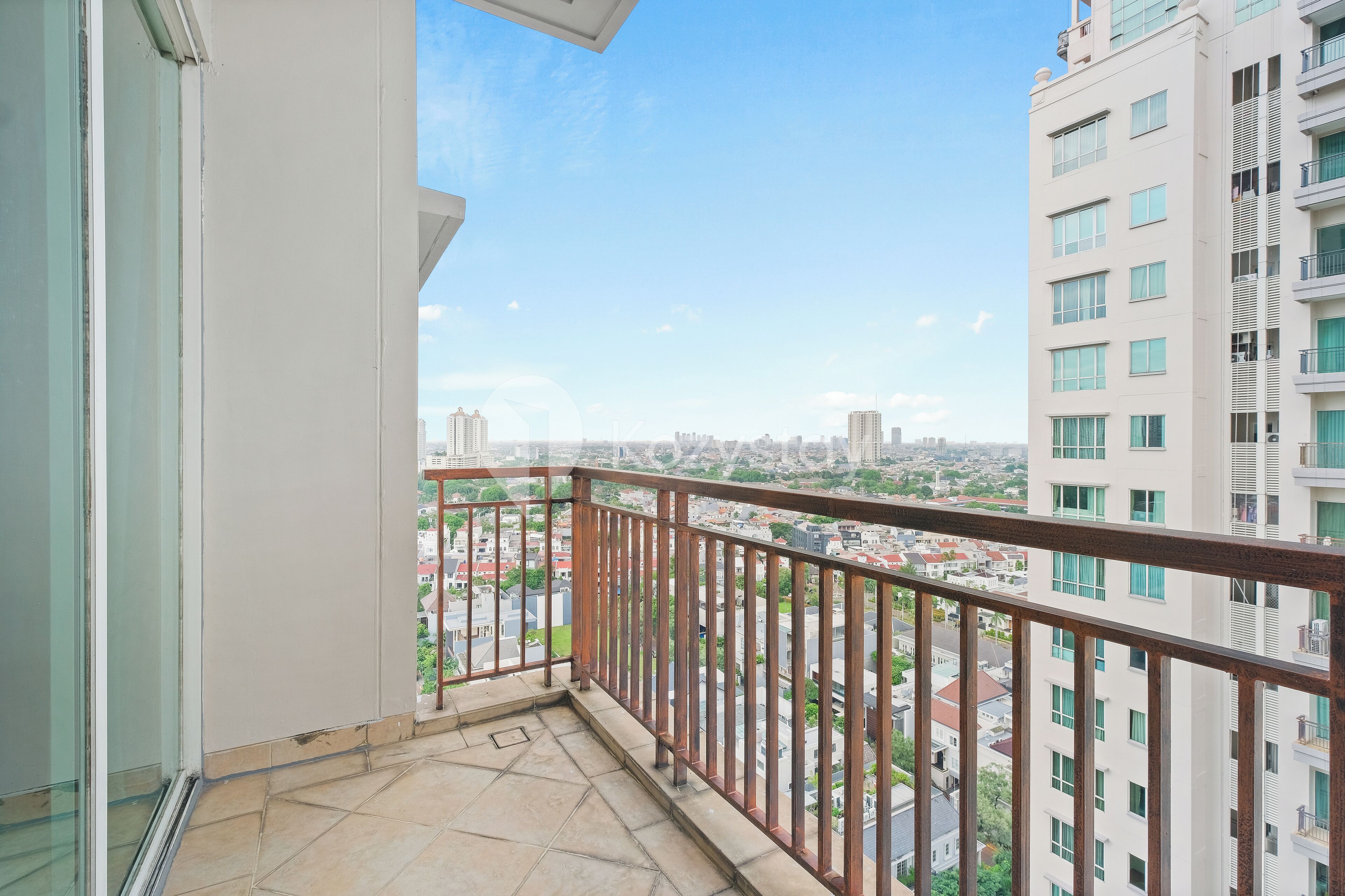A balcony with a metal railing overlooking a cityscape.