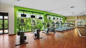 Een sportschool met trainingsapparatuur, grote ramen en een groene wand.