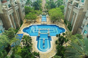 Ein Pool auf dem Dach mit einer zentralen Fontäne, umgeben von Palmen und einem gefliesten Gehweg.