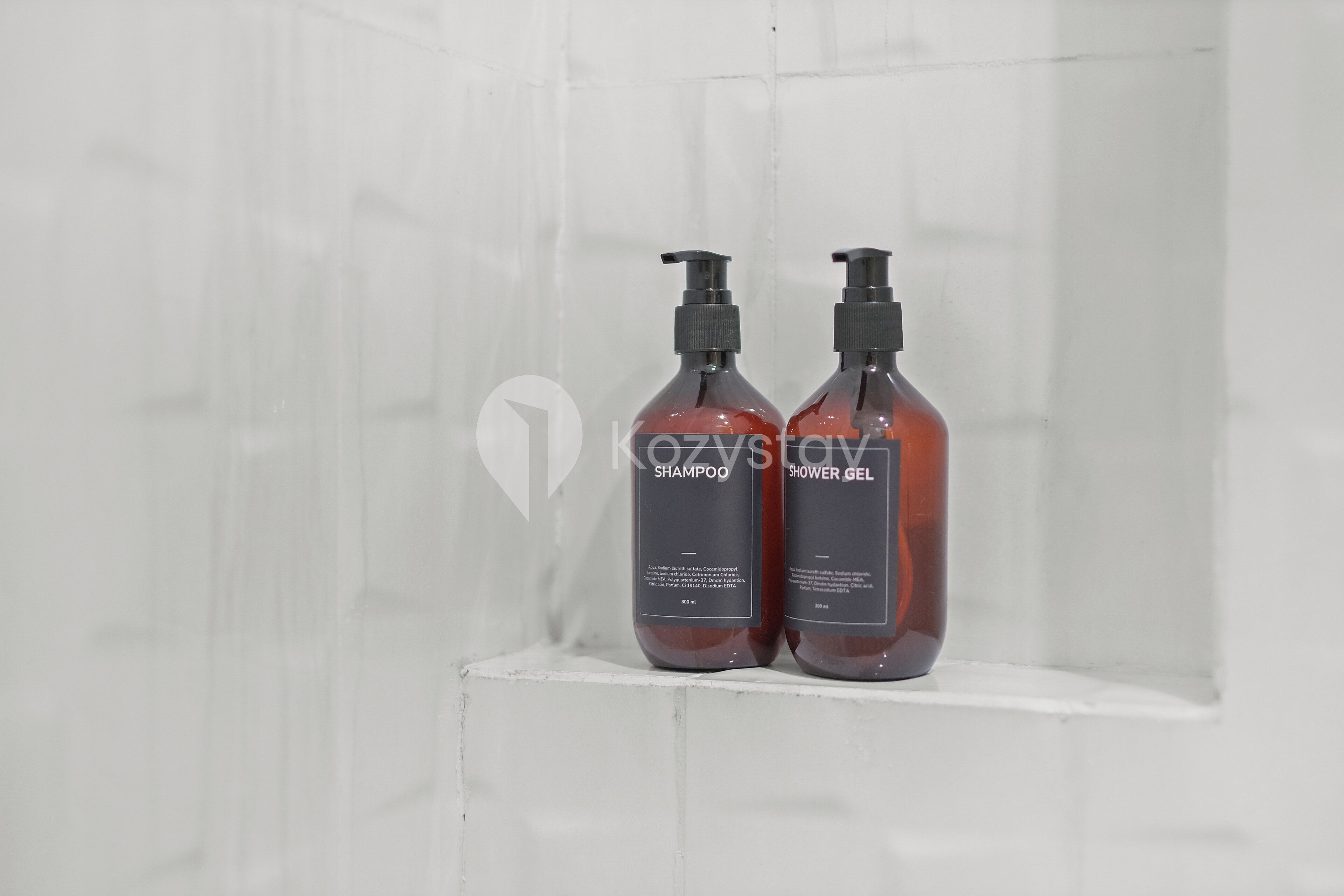 Two bottles of shampoo and shower gel on a white shelf.
