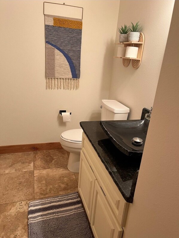 Une salle de bain équipée de toilettes, d’un lavabo et d’un porte-serviettes agrémenté d’une serviette décorative.