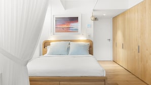 Un dormitorio con cama, mesita de noche, armario y un amplio ventanal.