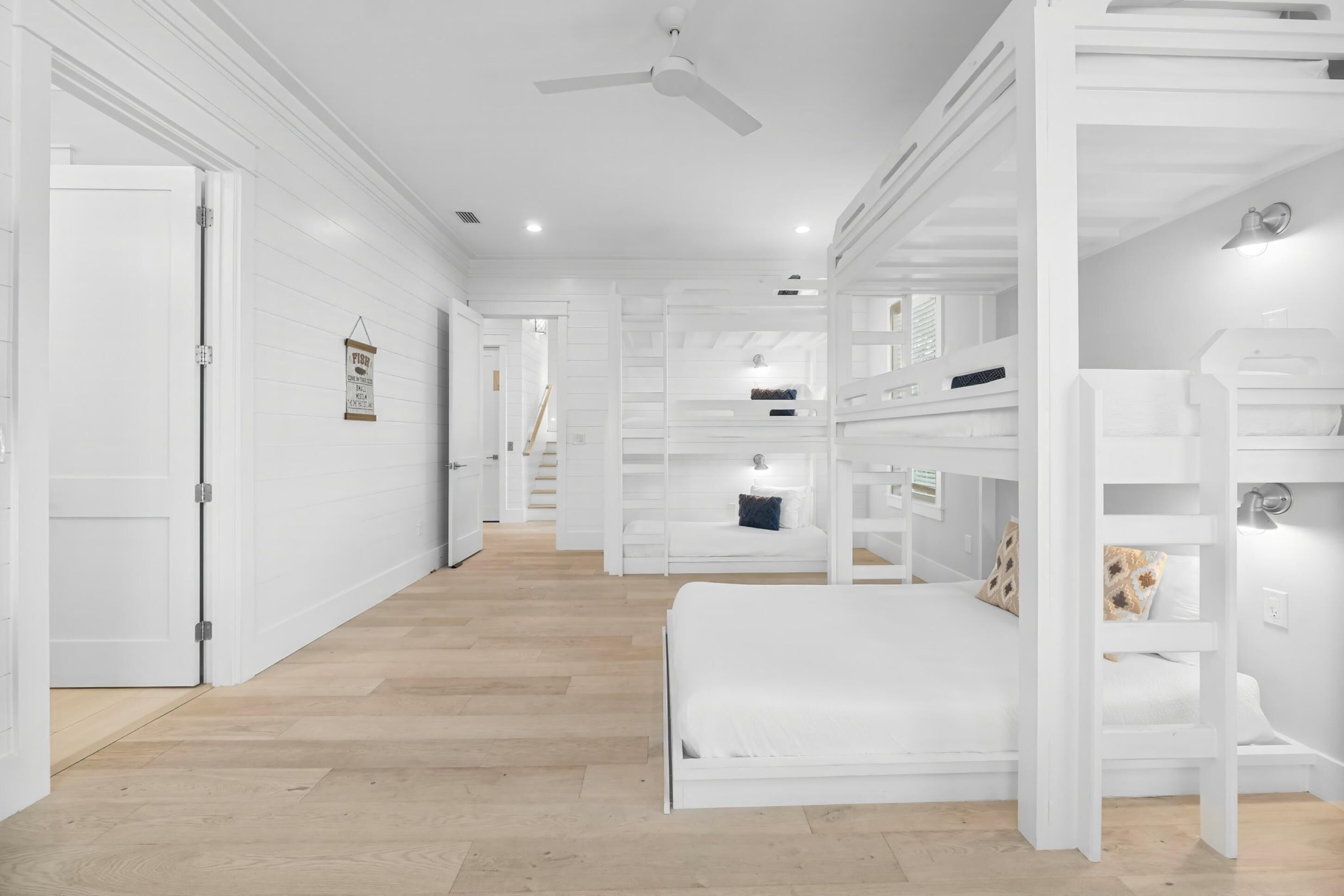 Ein helles Schlafzimmer mit Etagenbetten, Deckenventilator und Holzboden.