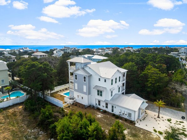 A large white two-story house with a swimming pool, surrounded by trees and other houses. - 30A Beach House - Dream by the Sea  (Santa Rosa Beach)