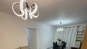 Un salon moderne avec un canapé d’angle, une table basse en verre et un coin repas comprenant une table et des chaises.