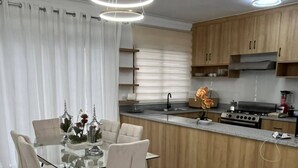Une cuisine moderne avec des meubles en bois, un îlot central et une table à manger en verre, accompagnée de chaises.