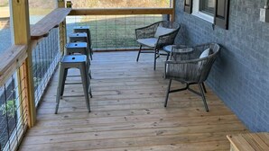 A covered porch with wooden flooring, a fan, and two wicker chairs. - Charming 2-bedroom bungalow in Smithfield with AC, WiFi, washer and dryer (Smithfield)