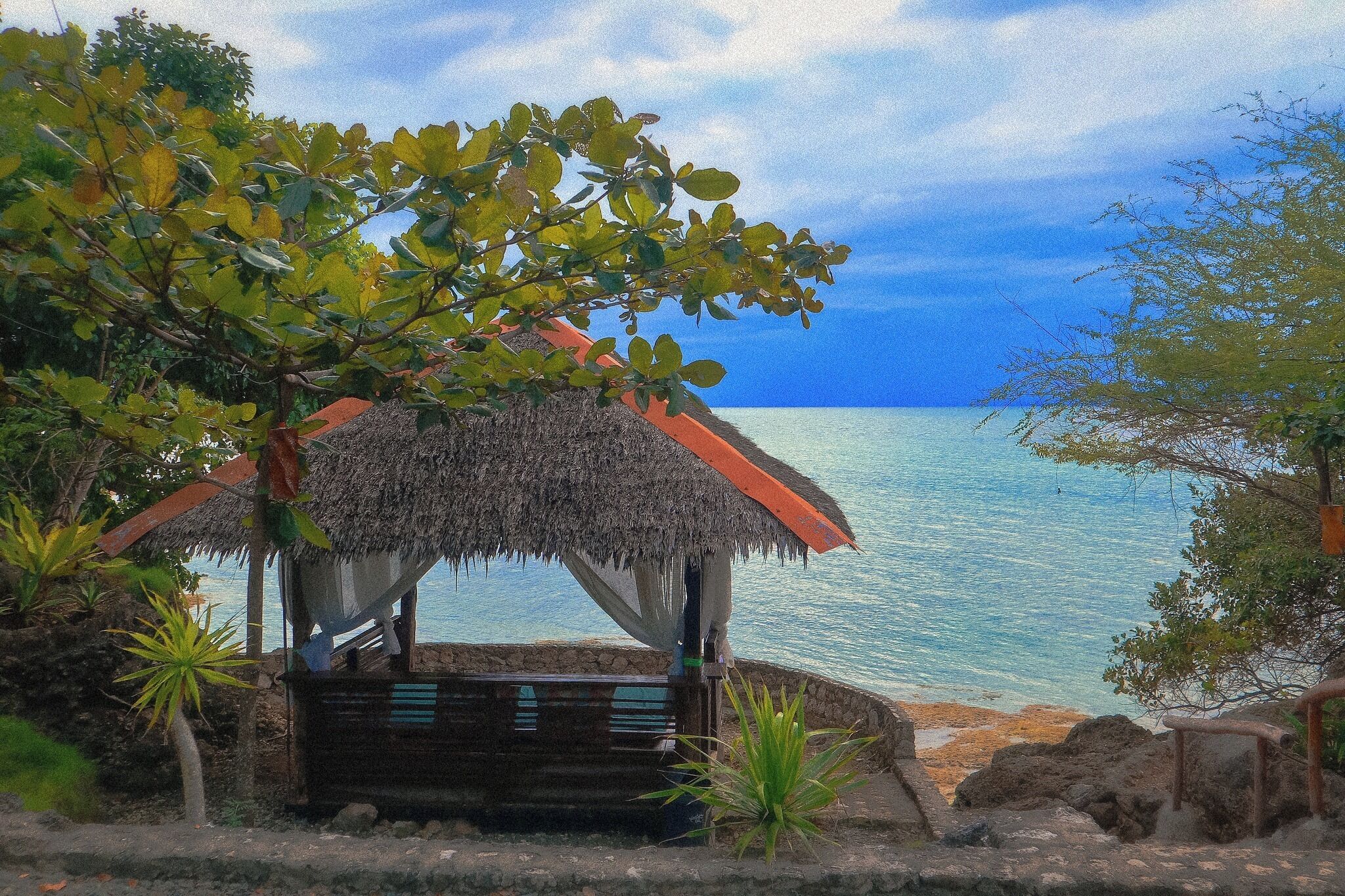 A thatched-roof hut with a view of the sea.